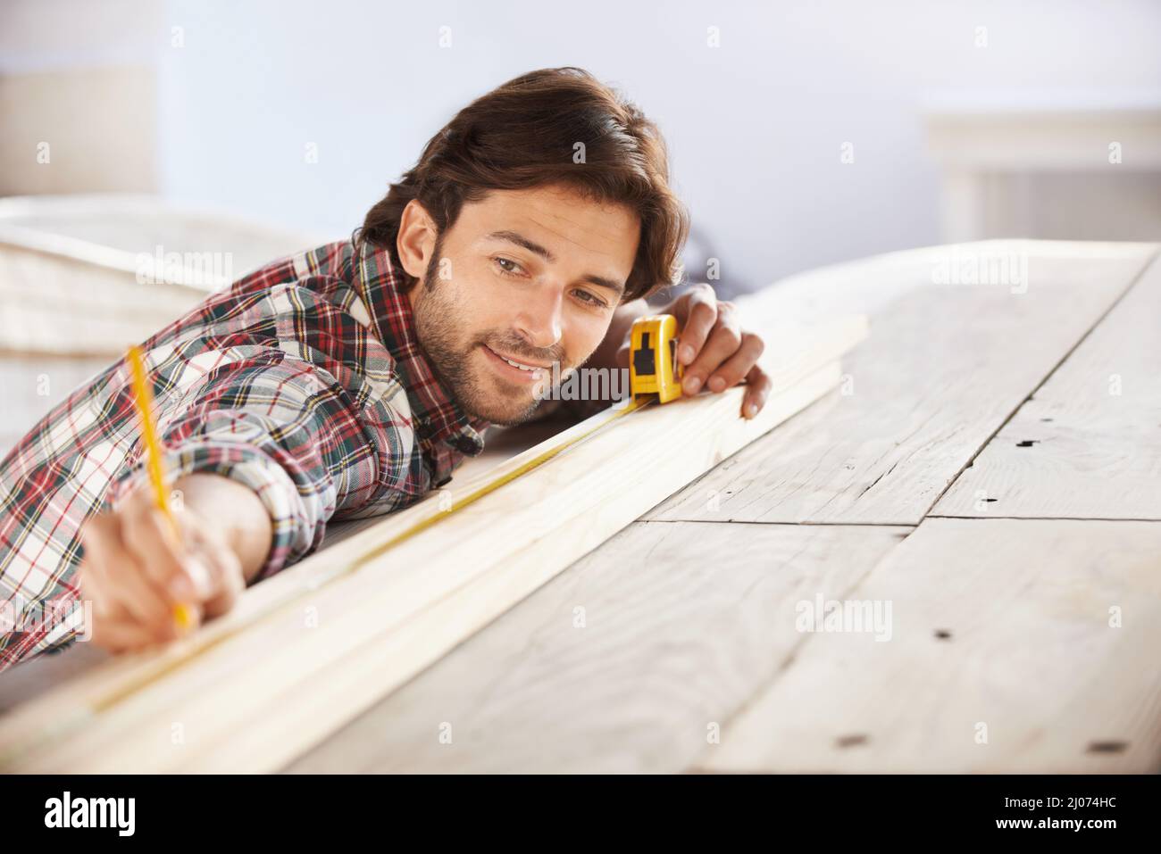 Perfetto. Un bel carpentiere giovane che misura e segna il legno. Foto Stock