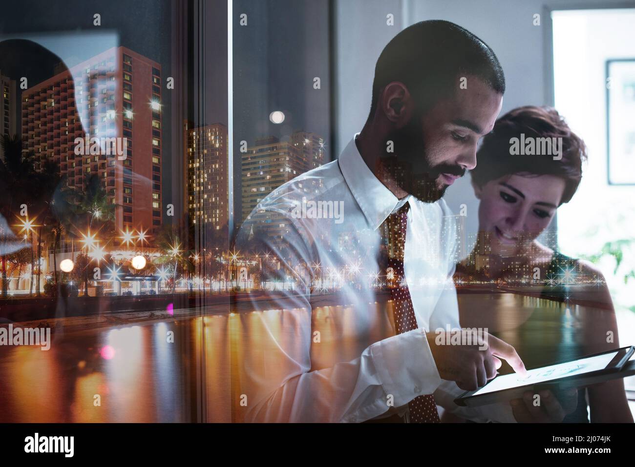 Sessioni di brainstorming a tarda notte. Esposizione multipla di colleghi utilizzando un tablet sovrapposto a una città. Foto Stock