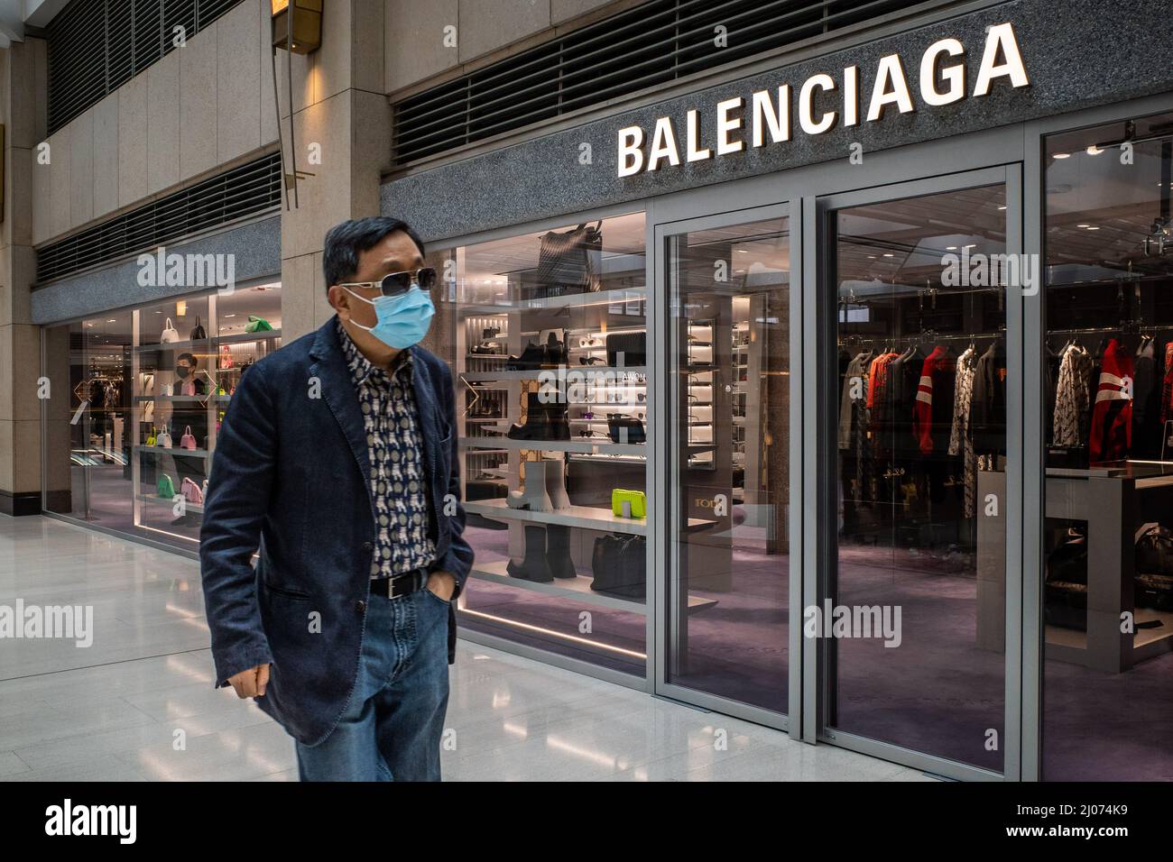 Hong Kong, Cina. 16th Mar 2022. Un uomo che indossa una maschera chirurgica  cammina presso un negozio Balenciaga nel quartiere Centrale degli Affari di  Hong Kong. Secondo l'analisi economica del governo di