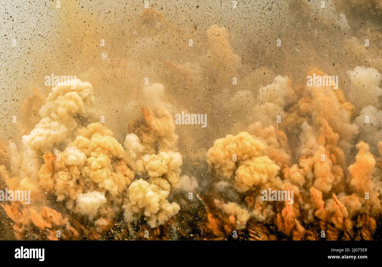 Fumi di polvere e detriti di roccia durante l'operazione di sabbiatura dei detonatori nel sito minerario dell'Oman Foto Stock