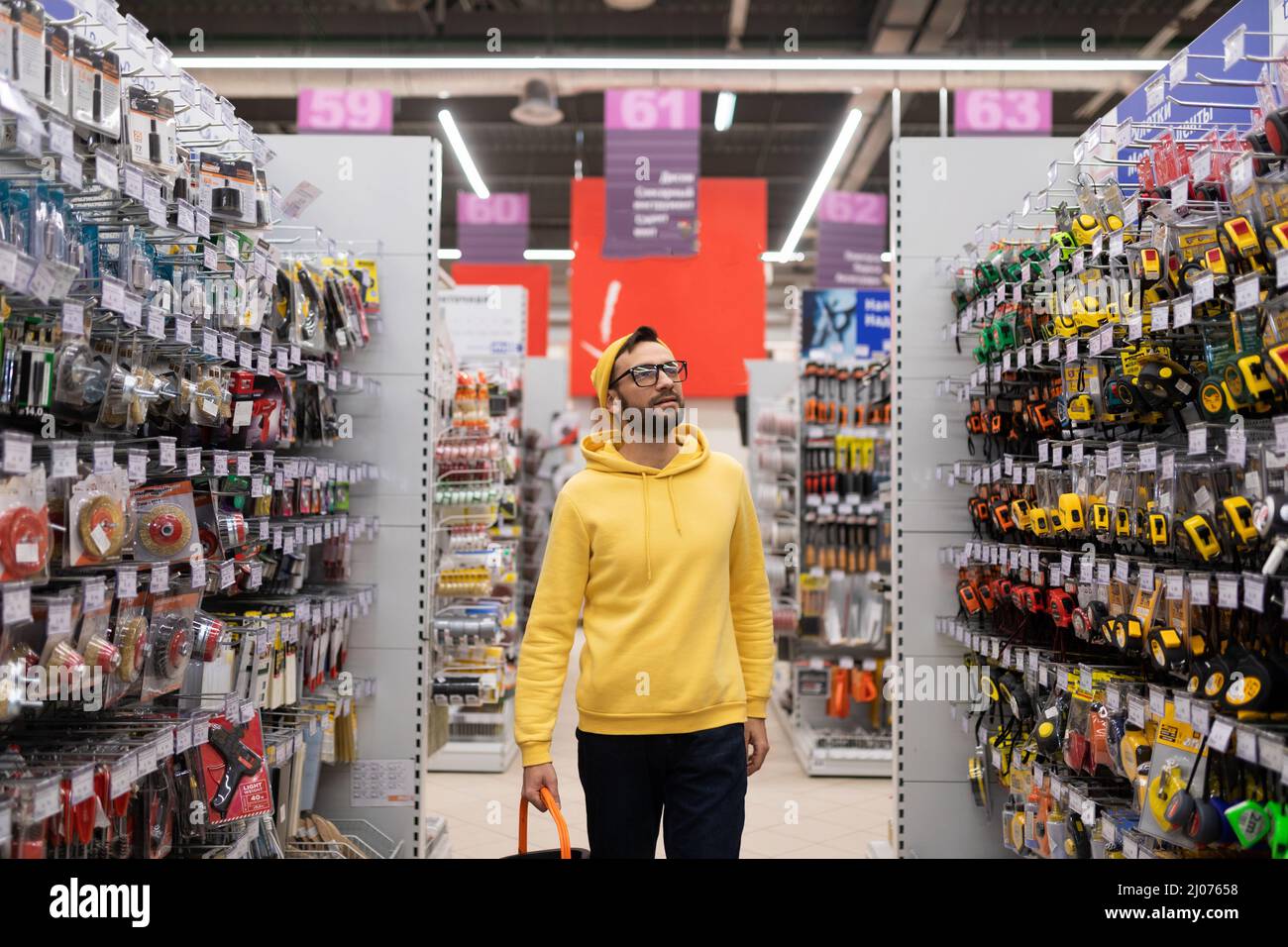 un cliente con un carrello di shopping si aggira intorno ad un ipermercato edile ed esamina la gamma dei prodotti Foto Stock