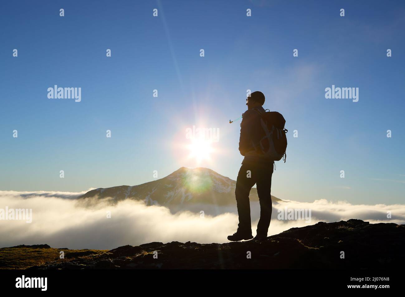 Hill Walker sulle pendici di Beinn Chuim guardando al sole sulla cima Blazoned di ben Lui che si infrangono attraverso l'inversione della nuvola in Scozia Foto Stock
