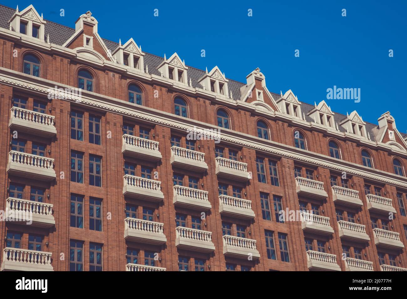 Splendido edificio in mattoni rossi con balconi color crema. Foto Stock