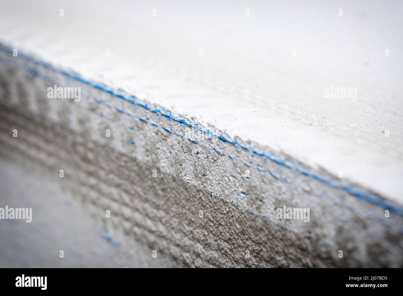 Nuovo cordone angolare di intonacatura con rete in plastica blu sull'angolo esterno di una finestra. Fuoco selettivo e profondità di campo poco profonda. Constructio Foto Stock