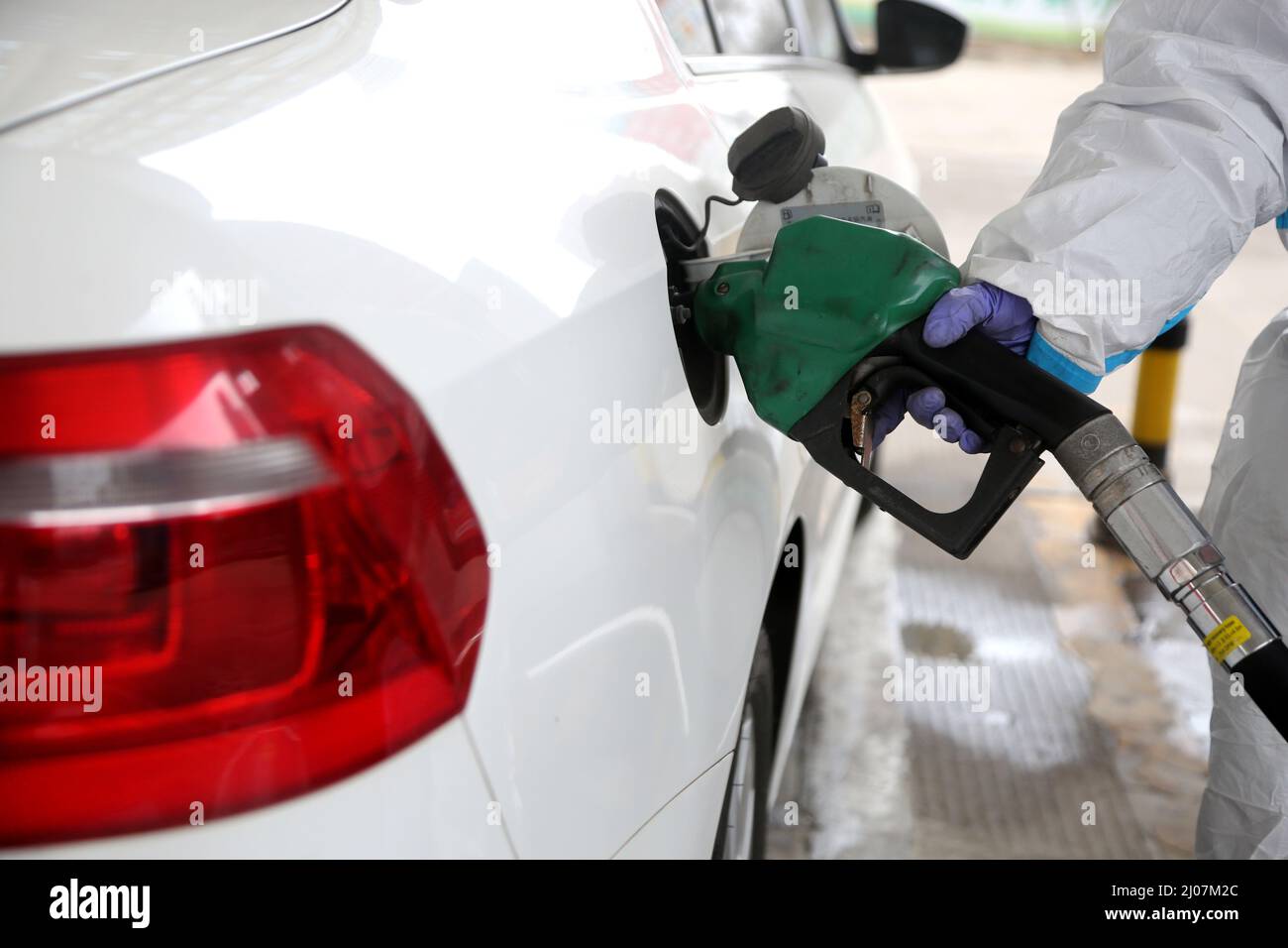 LIANYUNGANG, CINA - 17 MARZO 2022 - Un membro dello staff indossa abiti protettivi per alimentare un veicolo in una stazione di servizio nel distretto Lianyun di Lianyungang C. Foto Stock