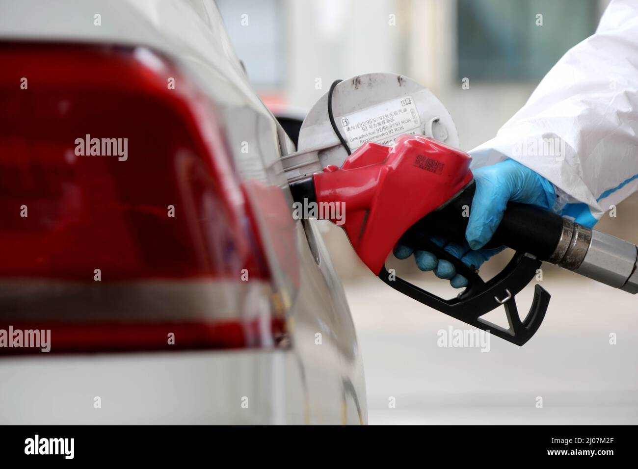 LIANYUNGANG, CINA - 17 MARZO 2022 - Un membro dello staff indossa abiti protettivi per alimentare un veicolo in una stazione di servizio nel distretto Lianyun di Lianyungang C. Foto Stock