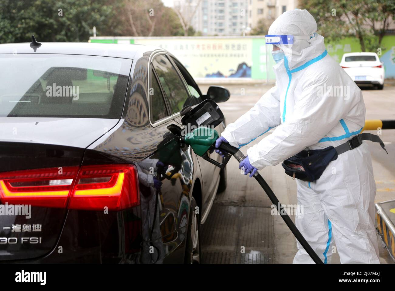 LIANYUNGANG, CINA - 17 MARZO 2022 - Un membro dello staff indossa abiti protettivi per alimentare un veicolo in una stazione di servizio nel distretto Lianyun di Lianyungang C. Foto Stock