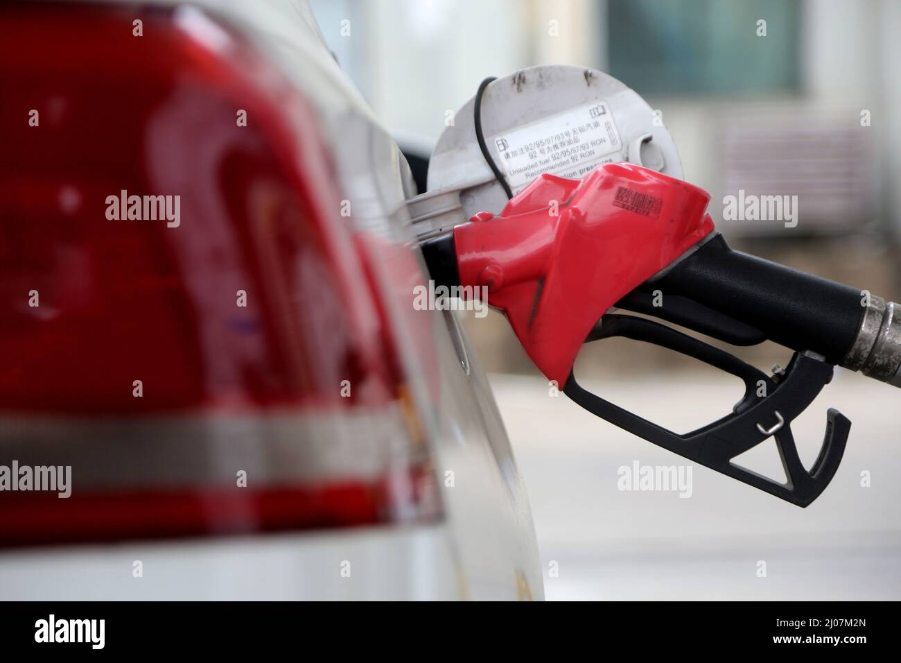 LIANYUNGANG, CINA - 17 MARZO 2022 - Un membro dello staff indossa abiti protettivi per alimentare un veicolo in una stazione di servizio nel distretto Lianyun di Lianyungang C. Foto Stock