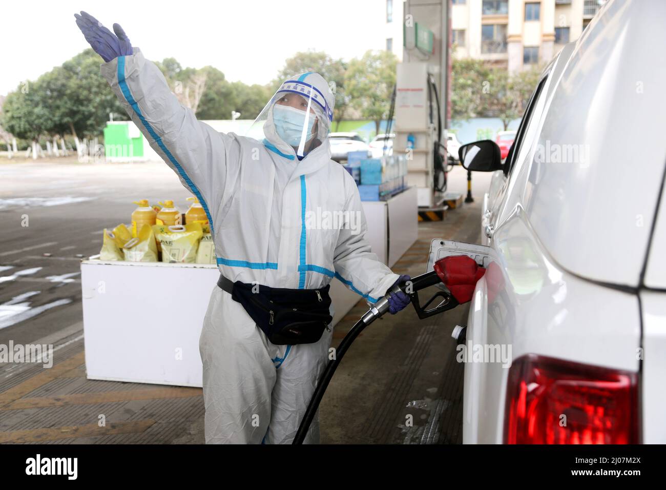 LIANYUNGANG, CINA - 17 MARZO 2022 - Un membro dello staff indossa abiti protettivi per alimentare un veicolo in una stazione di servizio nel distretto Lianyun di Lianyungang C. Foto Stock
