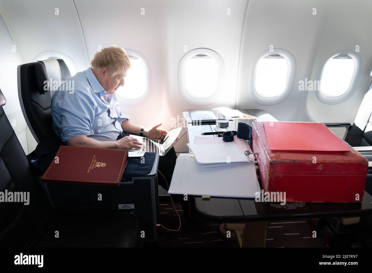 Il primo ministro Boris Johnson lavora a bordo del suo aereo mentre ritorna dall'Arabia Saudita dopo aver trascorso una giornata negli Emirati Arabi Uniti e in Arabia Saudita per rafforzare i legami con le nazioni del Golfo. Data foto: Giovedì 17 marzo 2022. Foto Stock