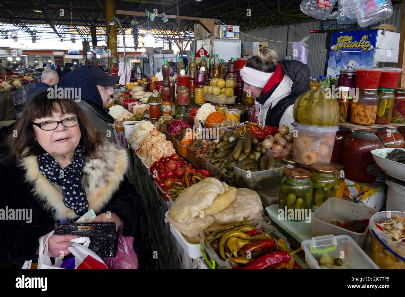ODESA, UCRAINA - 16 MARZO 2022 - Una donna passa una stalla con cibi conservati in casa al mercato di Pryvoz in Odesa, nel sud dell'Ucraina. Foto Stock