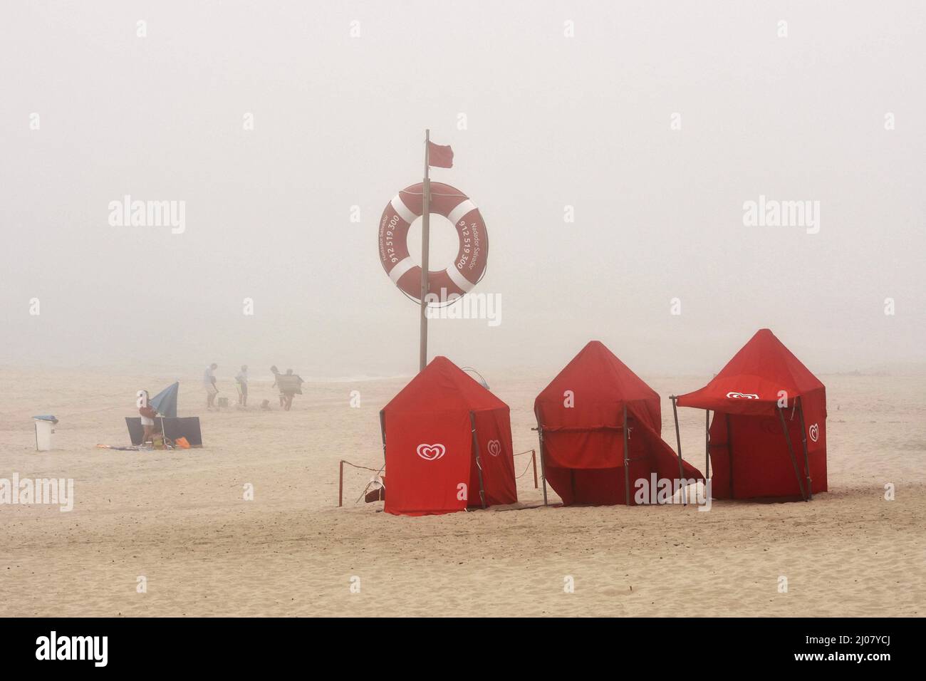 Tende e lifbuoy sulla spiaggia di Praia da Costa Nova, pomeriggio di nebbia in Aveiro Portogallo. Foto Stock
