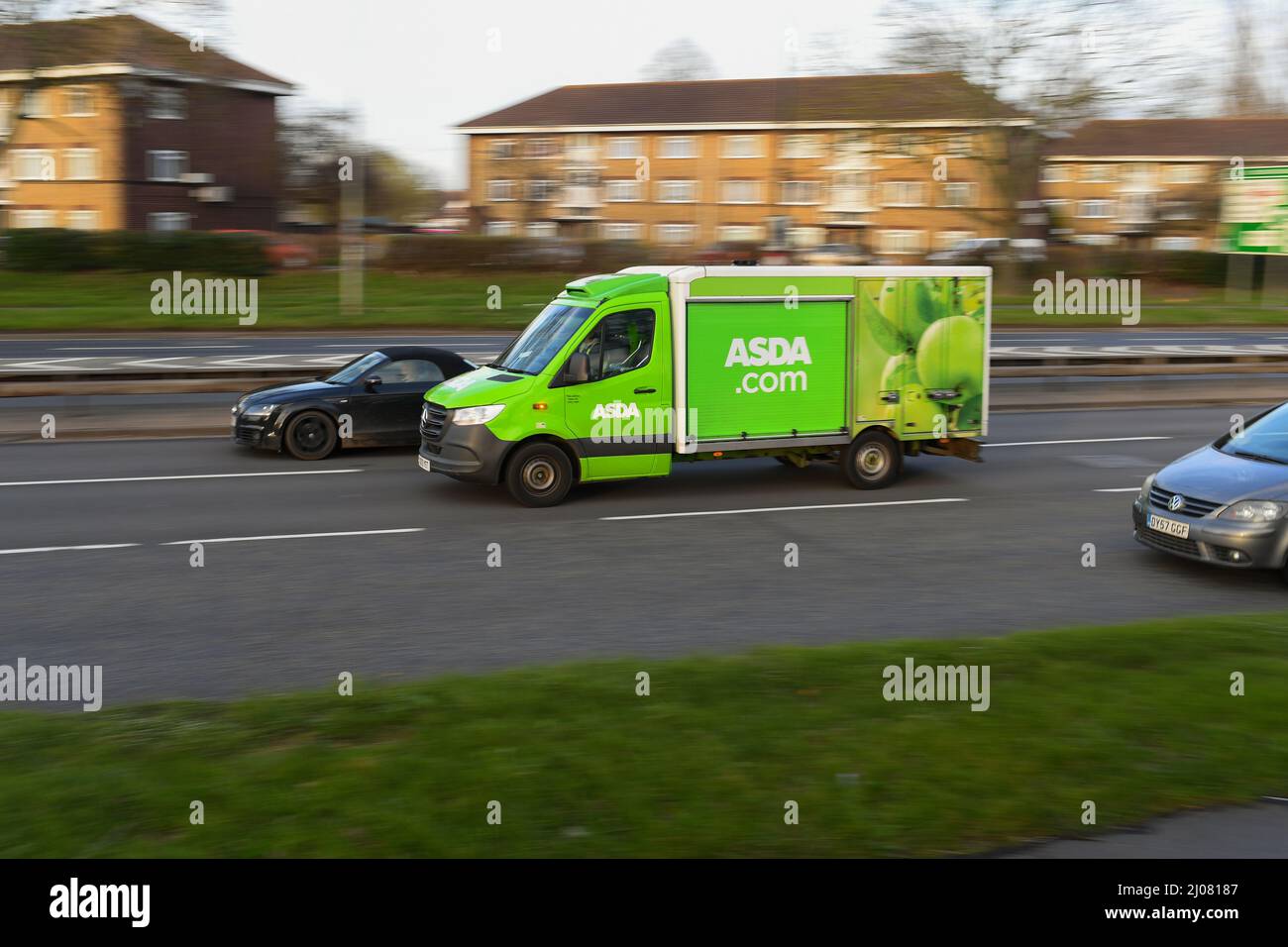 Asda online cibo shopping furgone di consegna guida lungo una strada trafficata in panning shot con spazio copia. Foto Stock