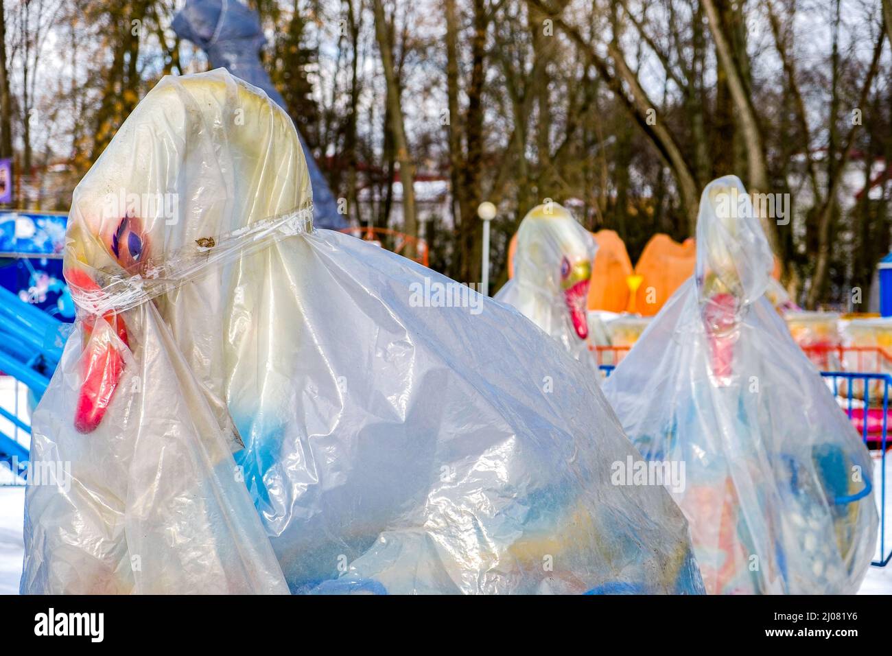 Tutto si è congelato. L'attrazione della giostra di cigno nel parco è chiusa e nascosta in un involucro di plastica per l'inverno. Foto Stock