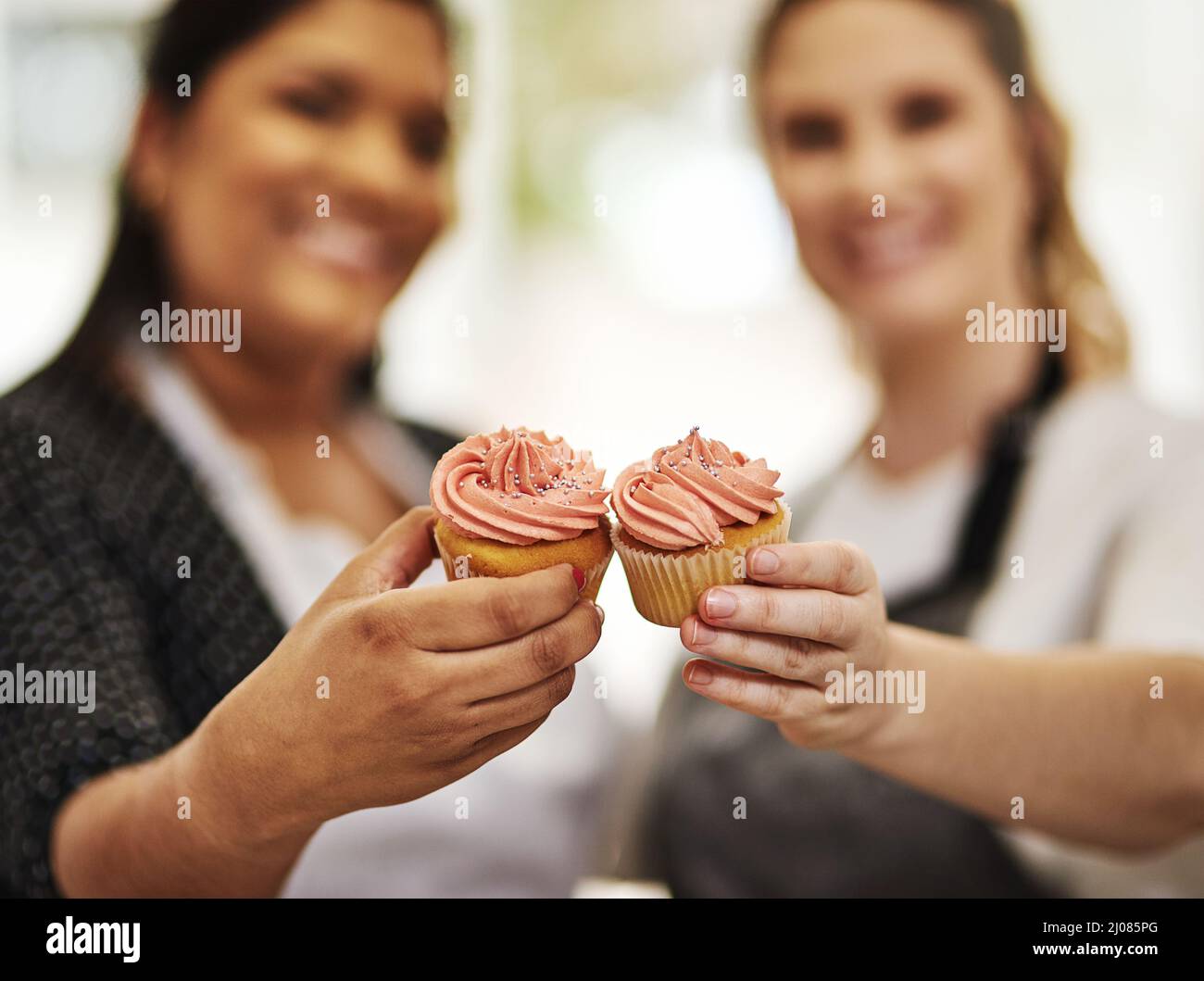 Beh, fai andare cupcake pazzo. Shot tagliato di due panettieri che tengono i cupcake. Foto Stock