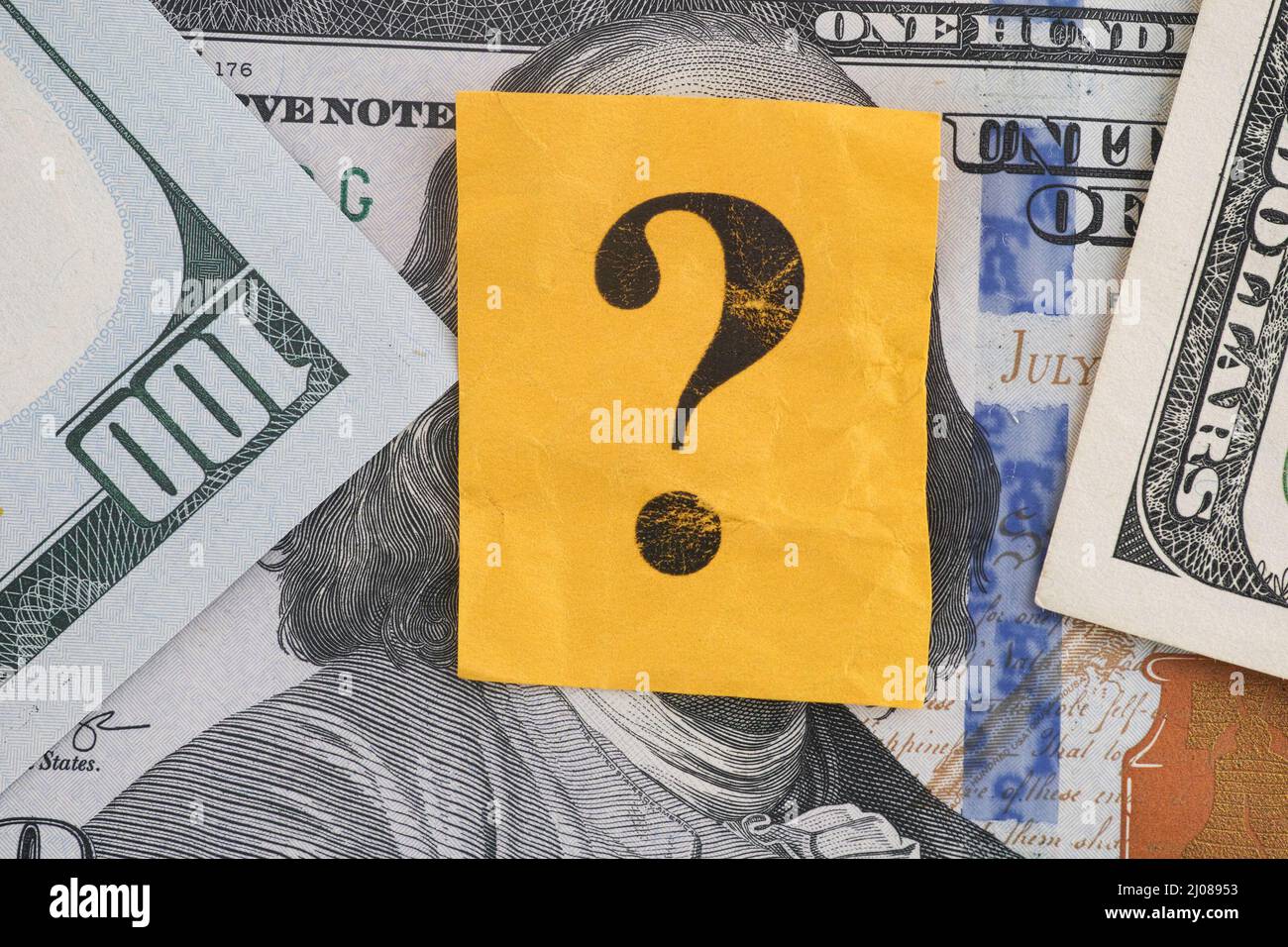 Un punto di domanda che giace su alcune fatture del dollaro. Primo piano. Foto Stock