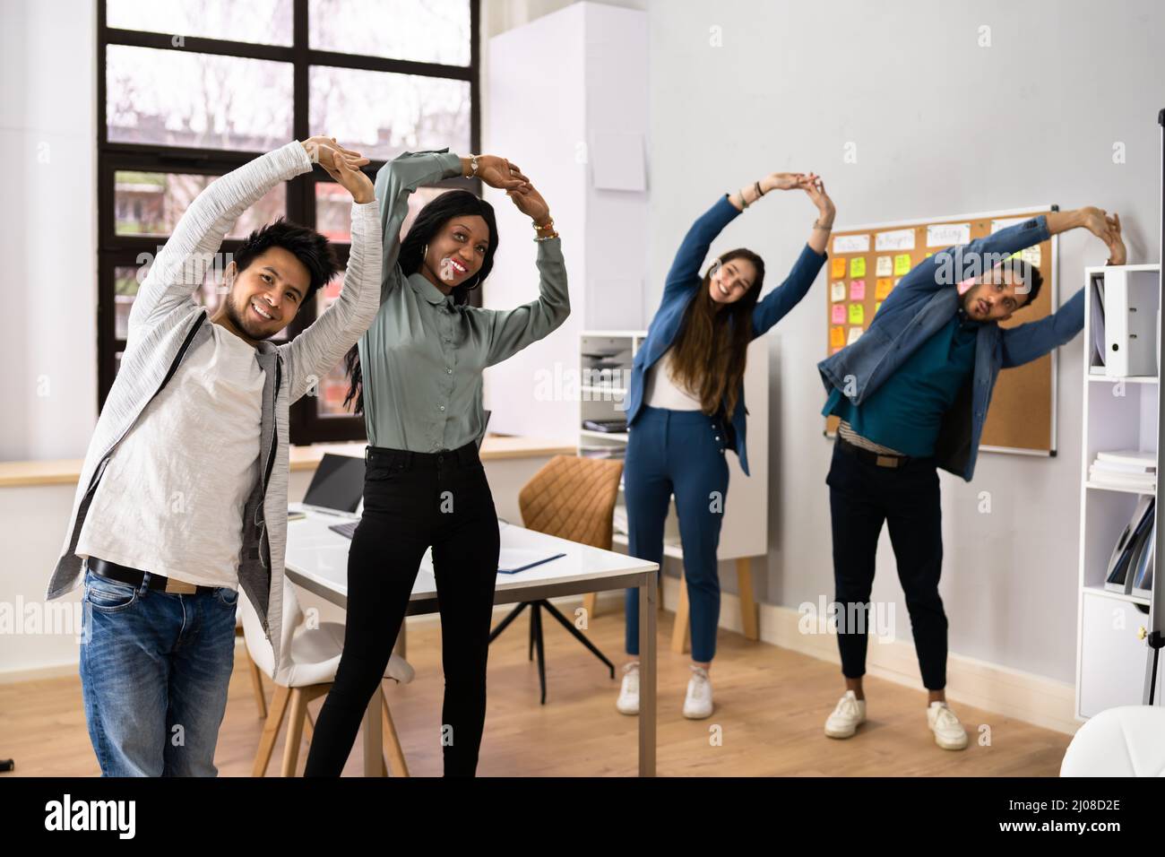 Gruppo di Felice Giovani Imprenditori facendo esercizio di stretching in ufficio Foto Stock