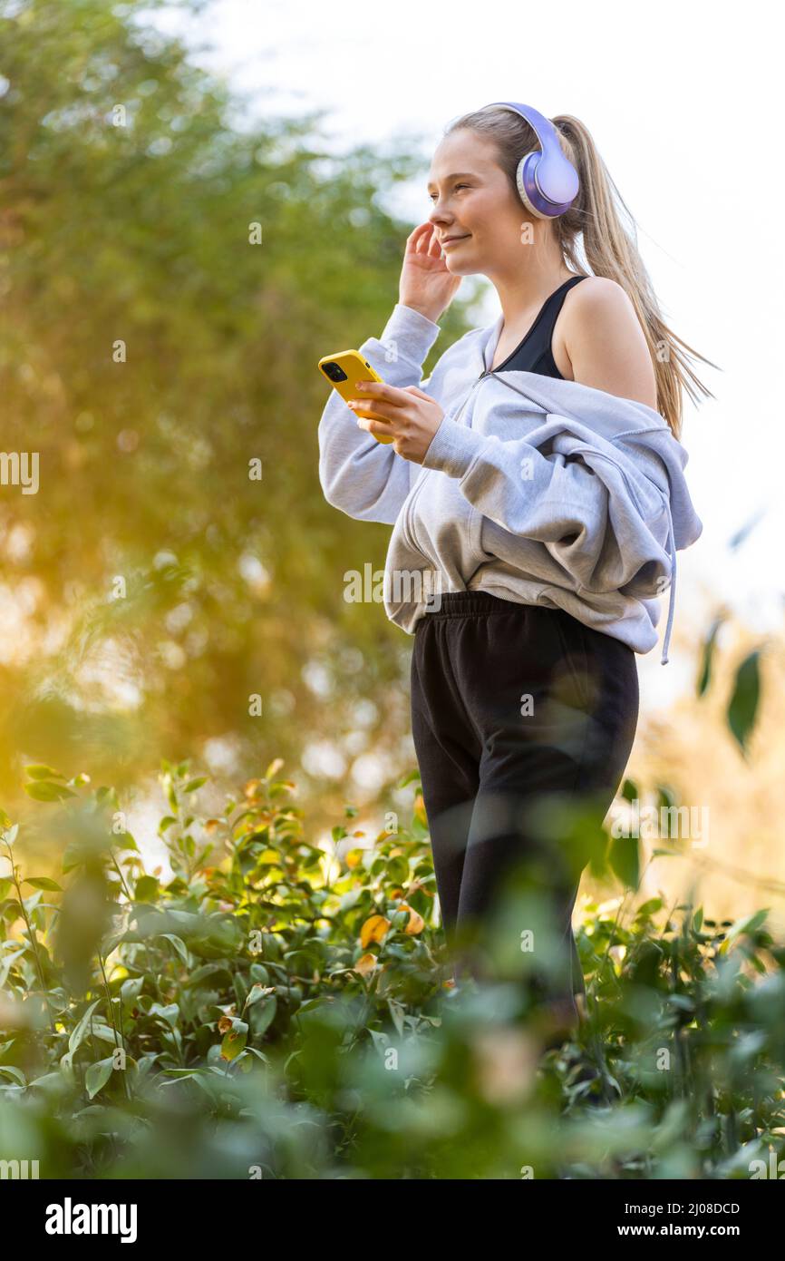 Giovane donna che fa sport e ascolta musica nel parco Foto Stock