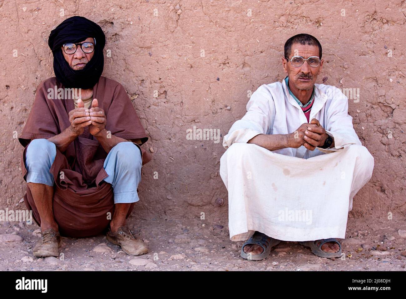 Due uomini locali seduti all'ombra in una città desertica di M'Hamid, nel sud del Marocco, in Africa Foto Stock