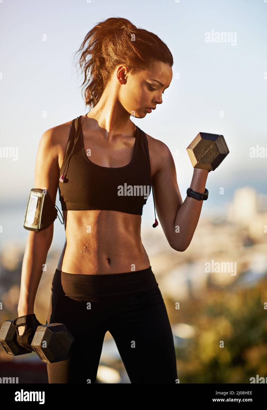 Fare i muscoli non scuse. Shot di una giovane donna che solleva manubri. Foto Stock