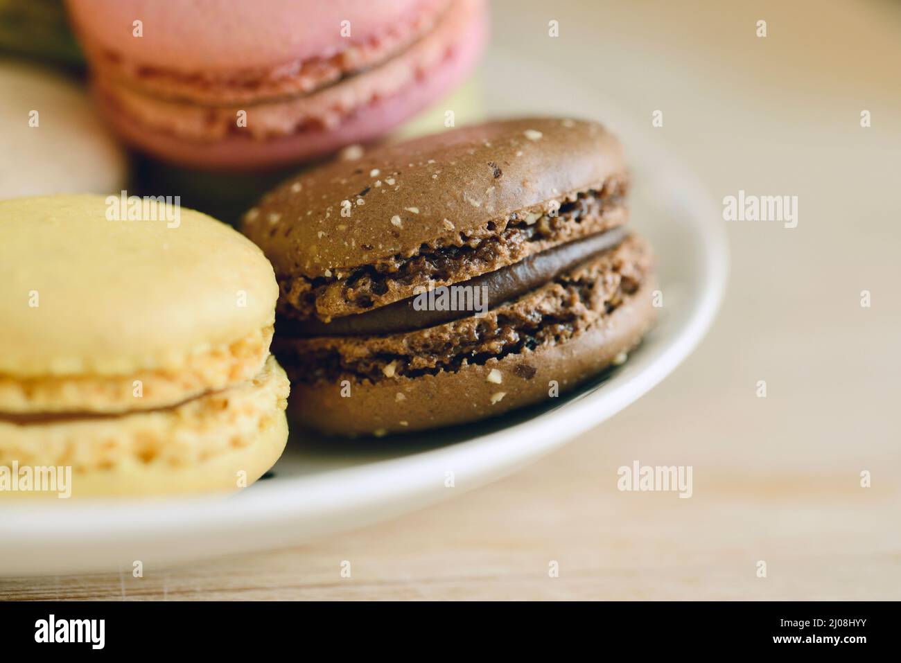 Primo piano di macaron di cioccolato, limone e lampone su un semplice piatto bianco Foto Stock Primo piano di macaron di cioccolato, limone e lampone su un semplice piatto bianco Foto Stock