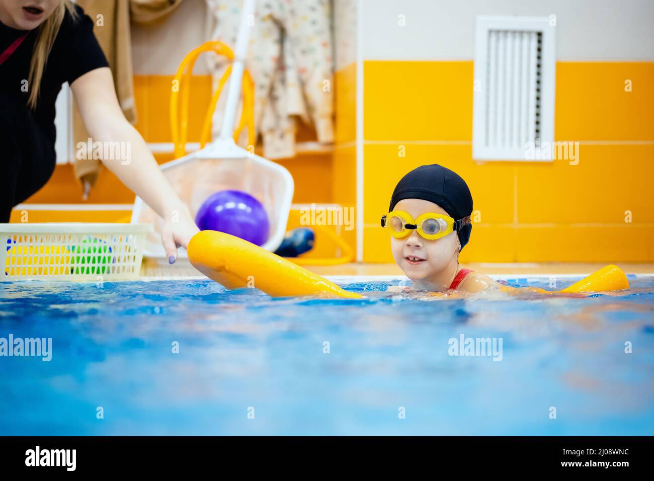 La bambina sta praticando il nuoto in costume da bagno rosa in piscina,  l'allenatore condurrà il nuoto di addestramento Foto stock - Alamy