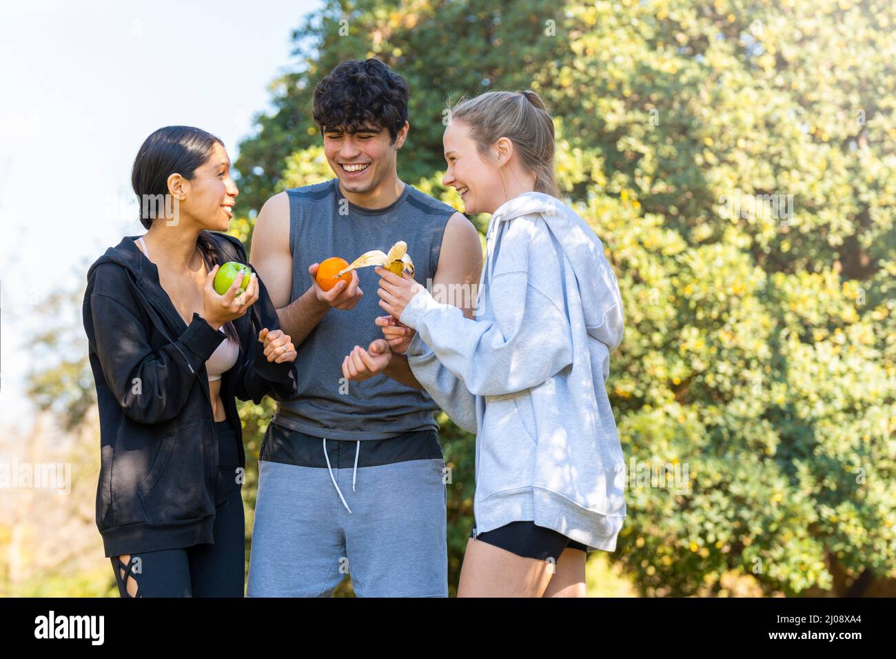 I giovani che praticano lo sport stanno facendo una pausa e mangiano frutta nel parco Foto Stock