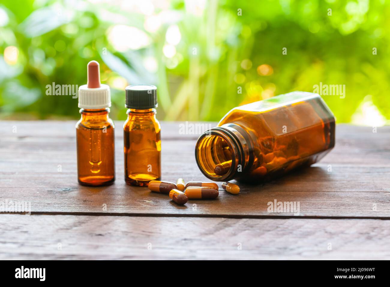 Alcune bottiglie e capsule mediche marroni su un tavolo di legno. Concetto omeopatico. Mettere a fuoco il primo piano. Foto Stock