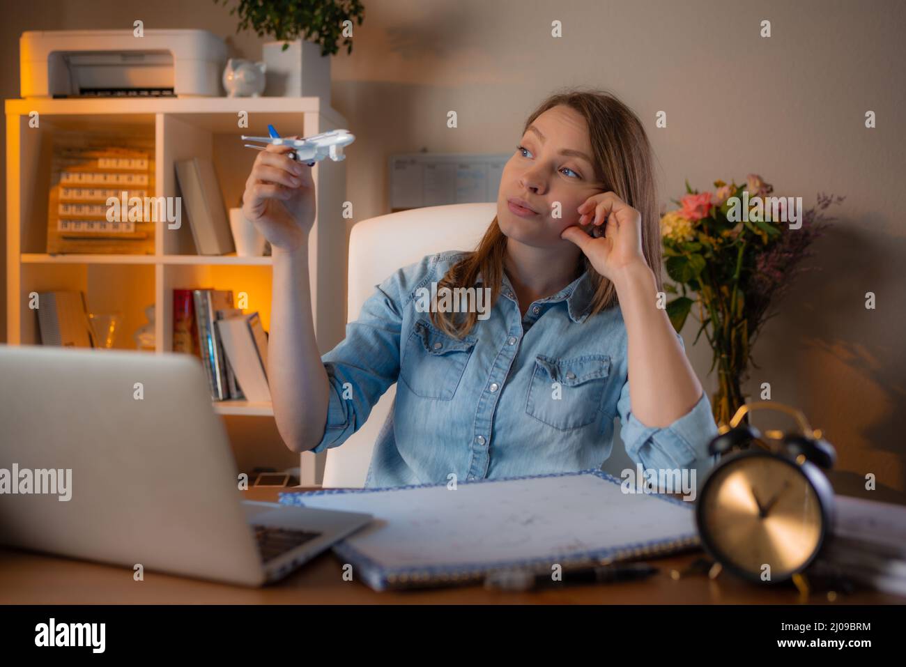 Bella donna sorridente che lavora al suo posto di lavoro in ufficio e sogna di viaggiare. Concetto di bel lavoro. Foto Stock