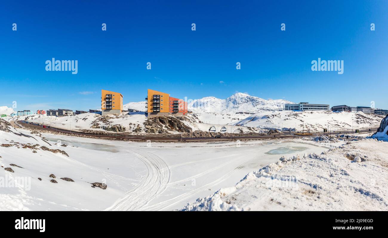 Paesaggio groenlandese con case a più piani Inuit della città di Nuuk sulle rocce con montagne sullo sfondo, Groenlandia Foto Stock