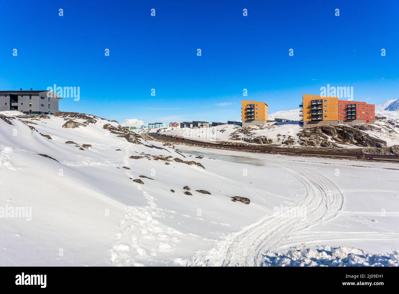 Paesaggio groenlandese con case a più piani Inuit della città di Nuuk sulle rocce con montagne sullo sfondo, Groenlandia Foto Stock