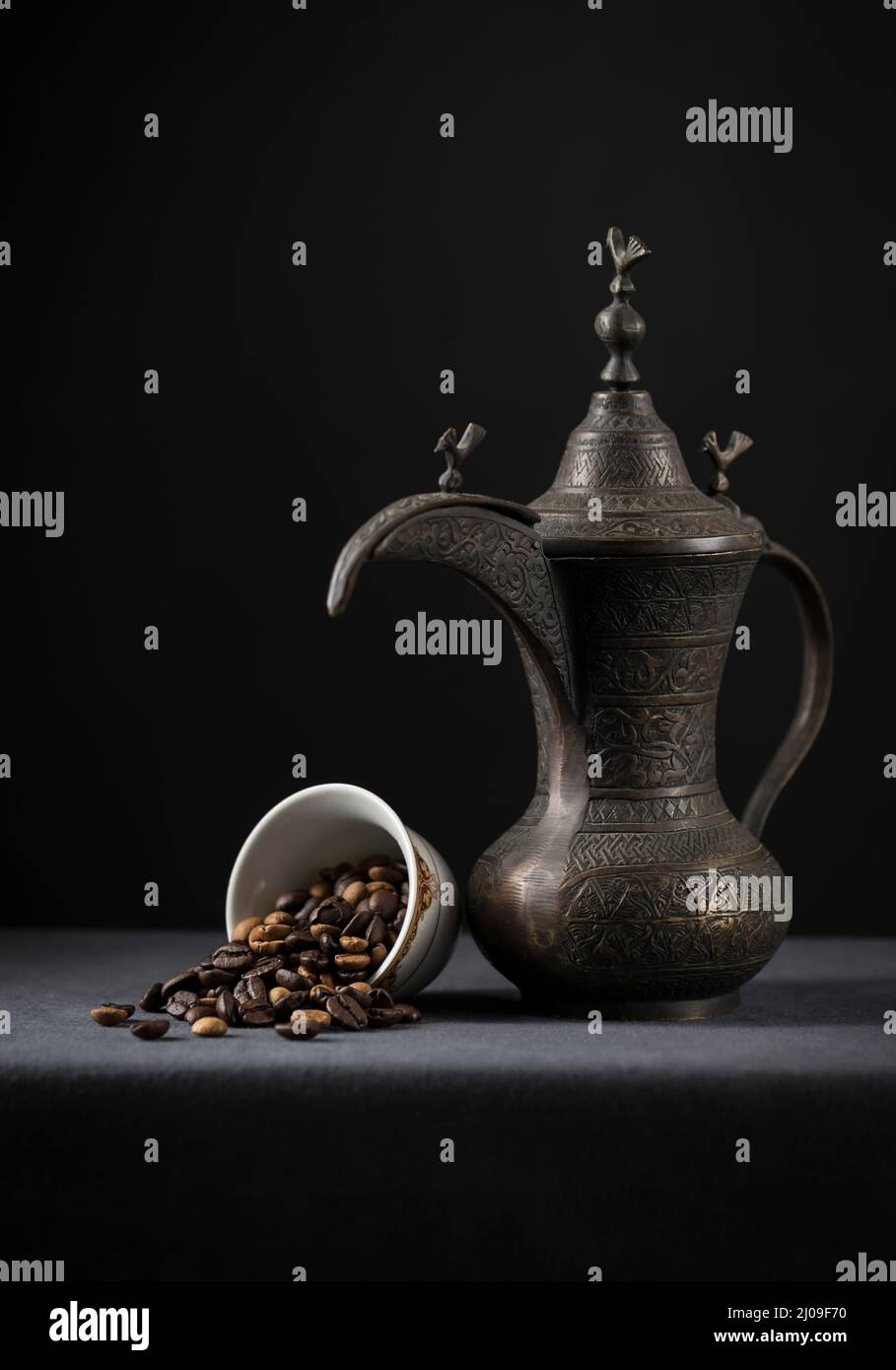 Antica caffettiera araba con chicchi di caffè torrefatto. I chicchi di caffè fuoriescono da una tazza. Fotografia di scorta. Foto Stock