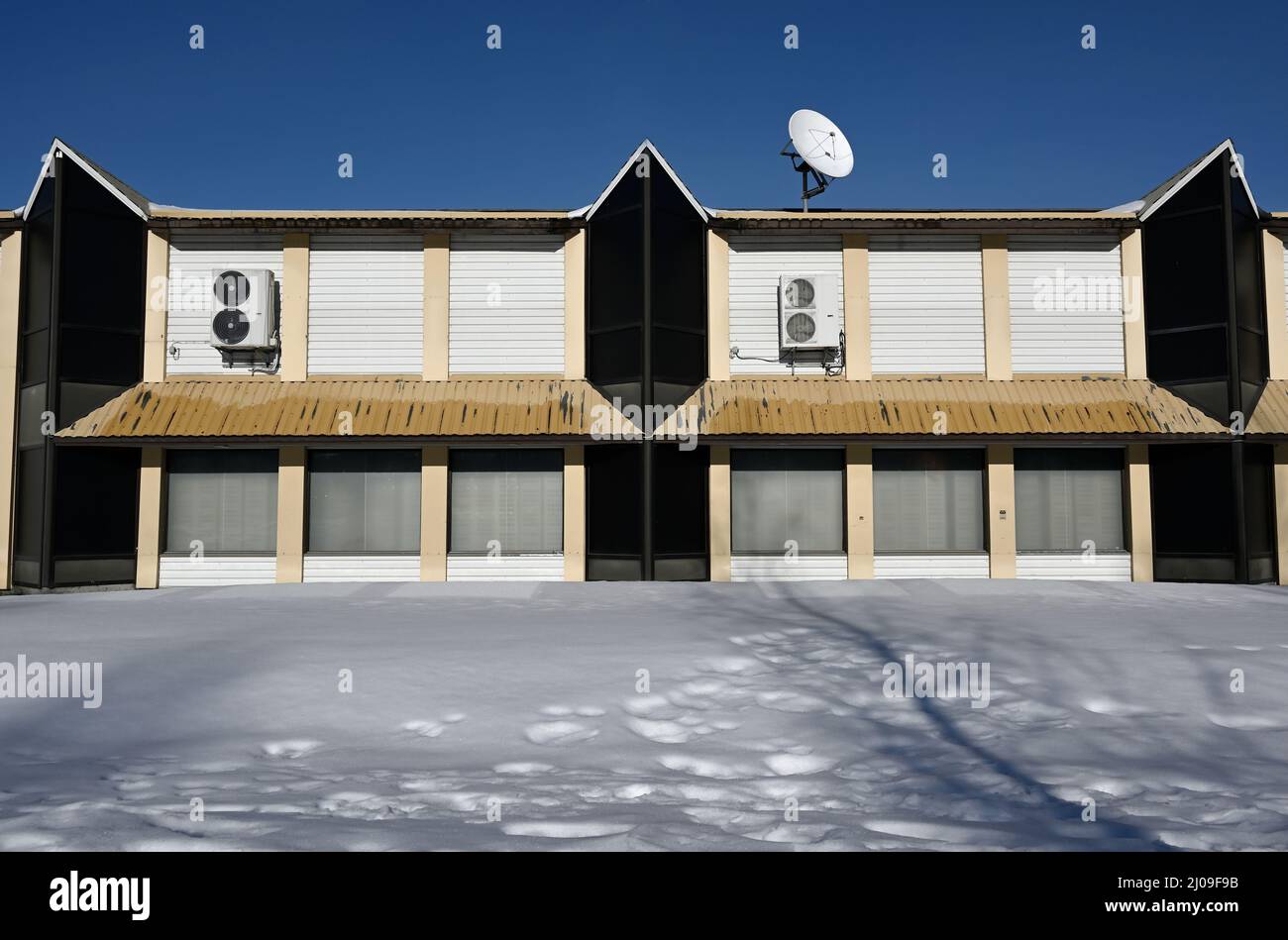 abbandonato edificio non residenziale con parabola satellitare sul tetto in inverno, deadpan fotografia Foto Stock