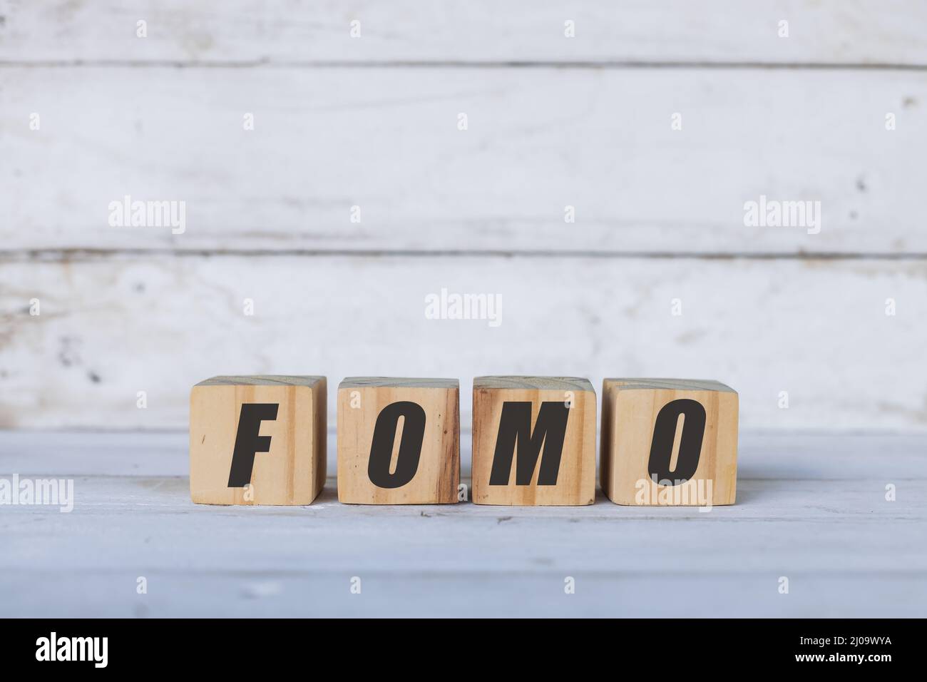 Concetto FOMO scritto su cubi o blocchi di legno, su sfondo bianco di legno. Foto Stock