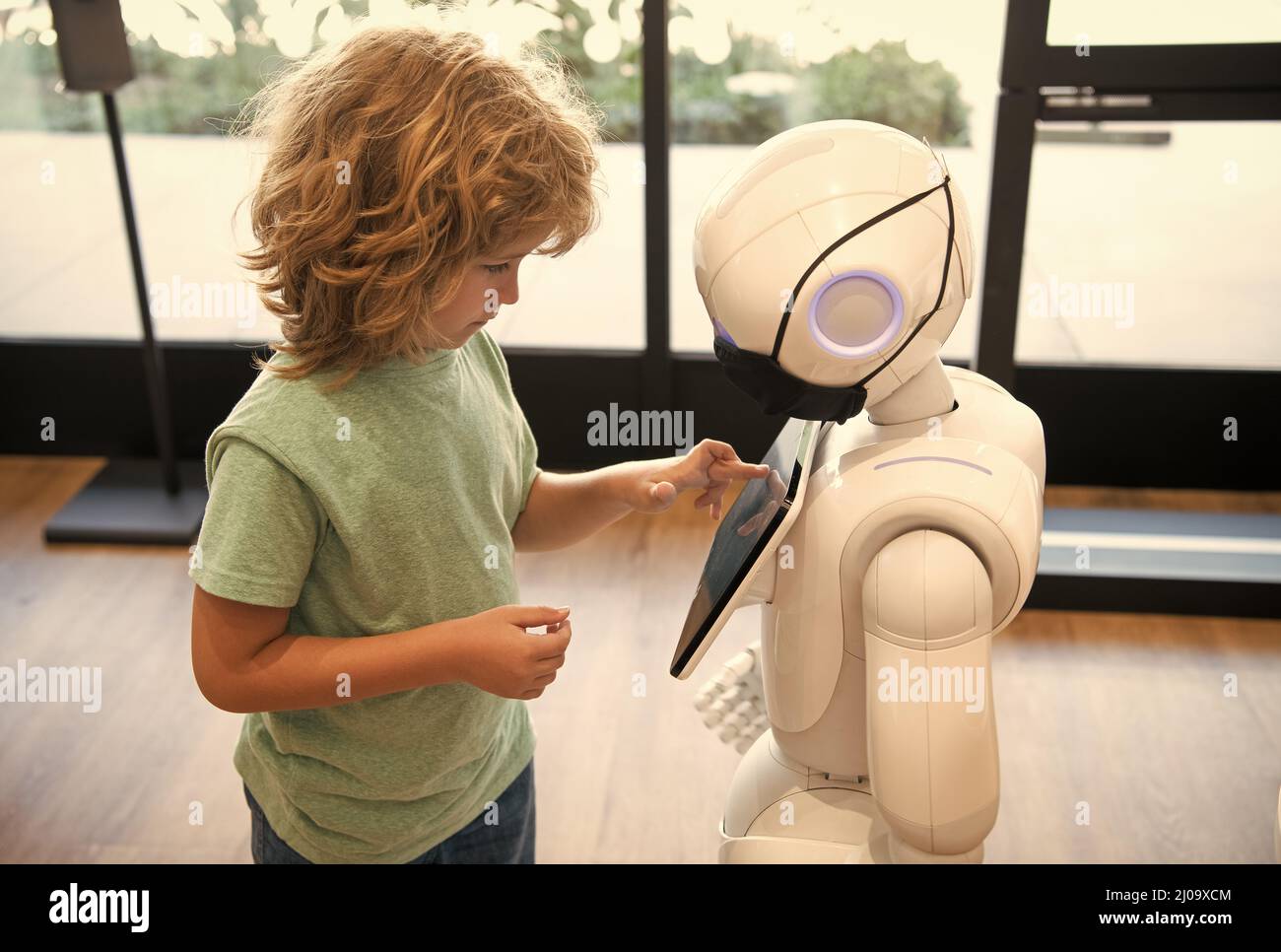 un piccolo ragazzo intelligente comunica con la tecnologia robot assistant per l'istruzione moderna, la robotica Foto Stock