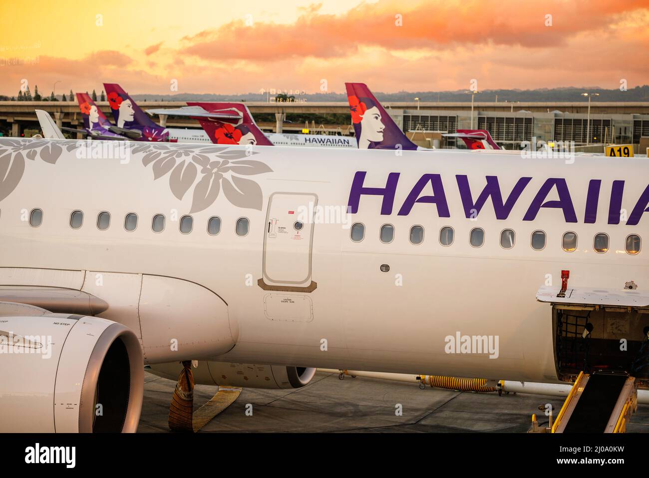 Una vista al tramonto attraverso i jet Hawaiian Airlines al Terminal InterIsland all'Aeroporto Internazionale di Honolulu, Oahu, Hawaii, USA. Foto Stock