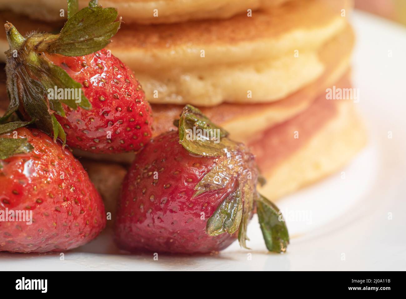 Primo piano di una fragola di fronte a torte calde su un piatto Foto Stock