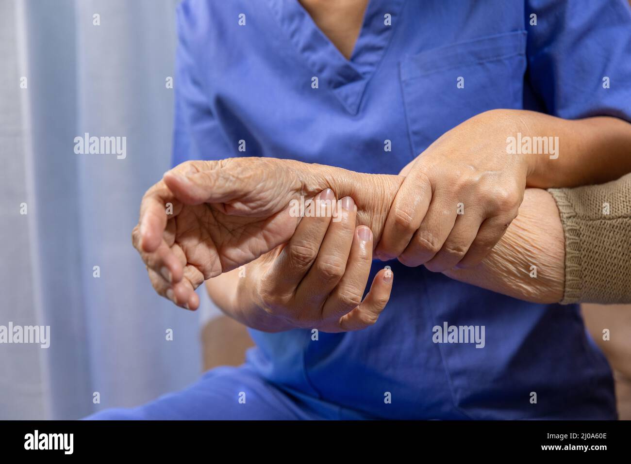 Caregiver massaggiando il polso di una donna anziana in gotta gonfia dolorosa . Foto Stock