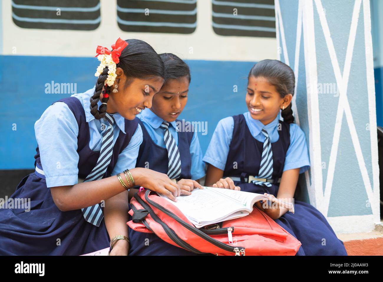 Gorup di ragazzi ragazze che studiano dal libro al corridoio della scuola durante la pausa - concetto di istruzione, apprendimento e conoscenza Foto Stock