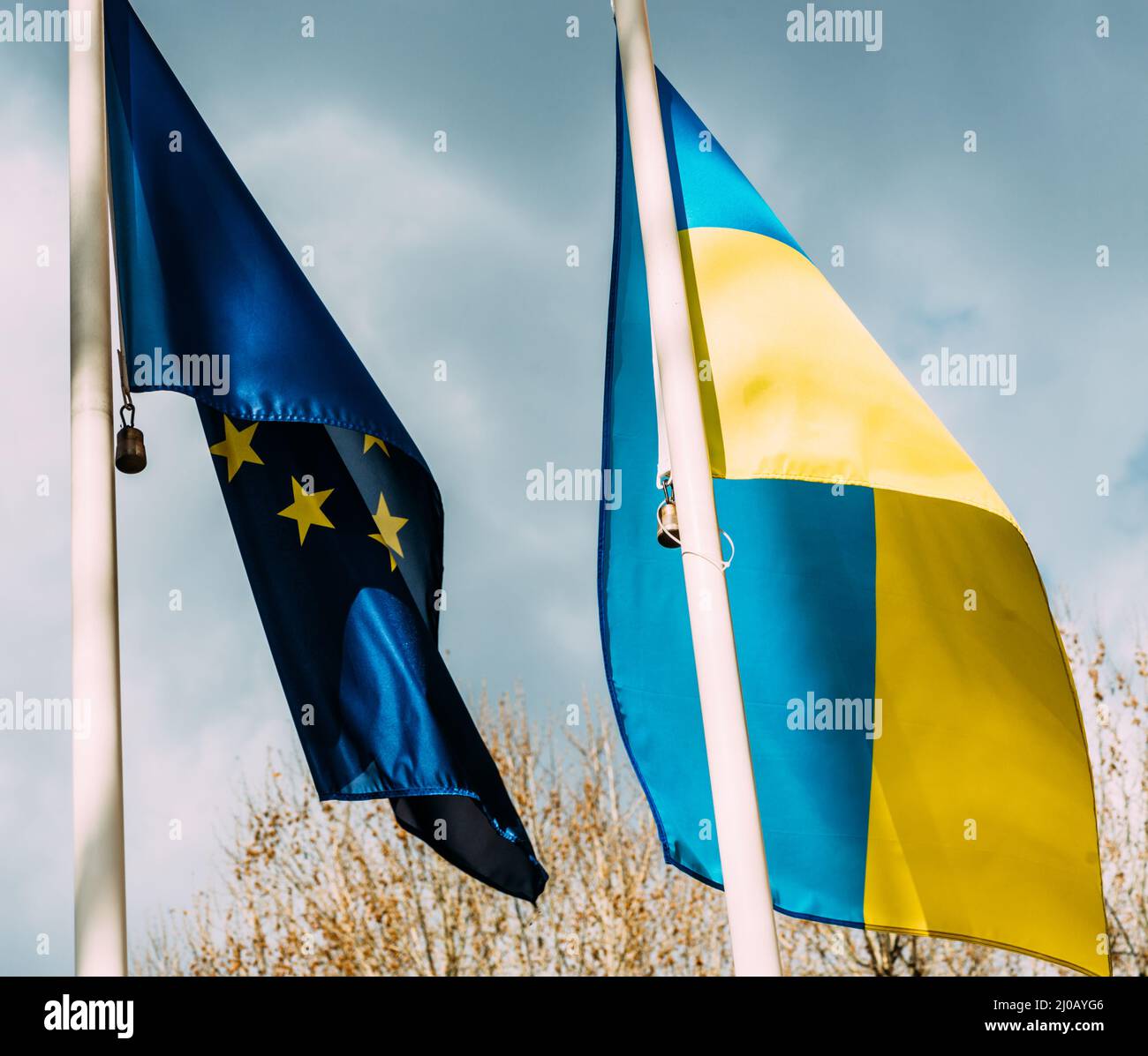 Un colpo vibrante di bandiere ucraine e dell'Unione europea che sbatte sul flagpole in una giornata di sole Foto Stock