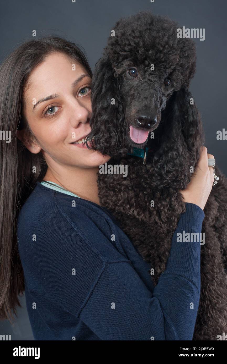 Ritratto di una bella giovane donna abbracciando il suo bel cane. Grande barattone nero. Riprese in studio Foto Stock