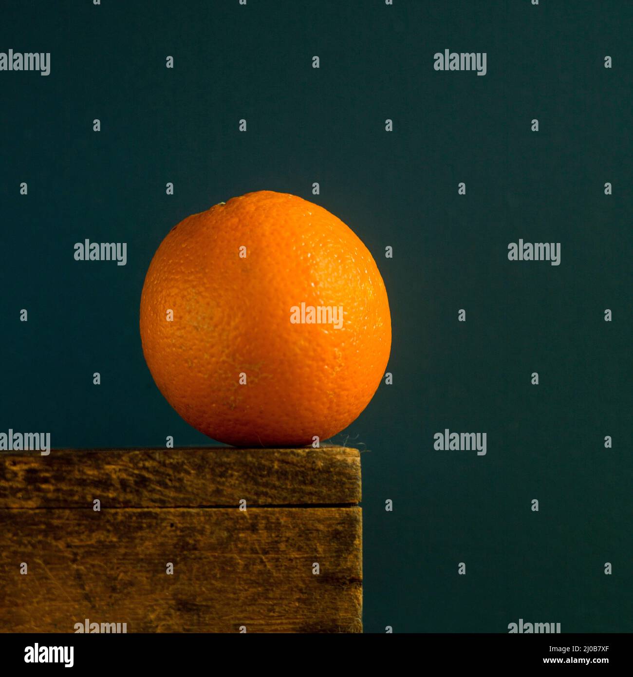 Un arancione vibrante che poggia su una superficie di legno su uno sfondo scuro Foto Stock