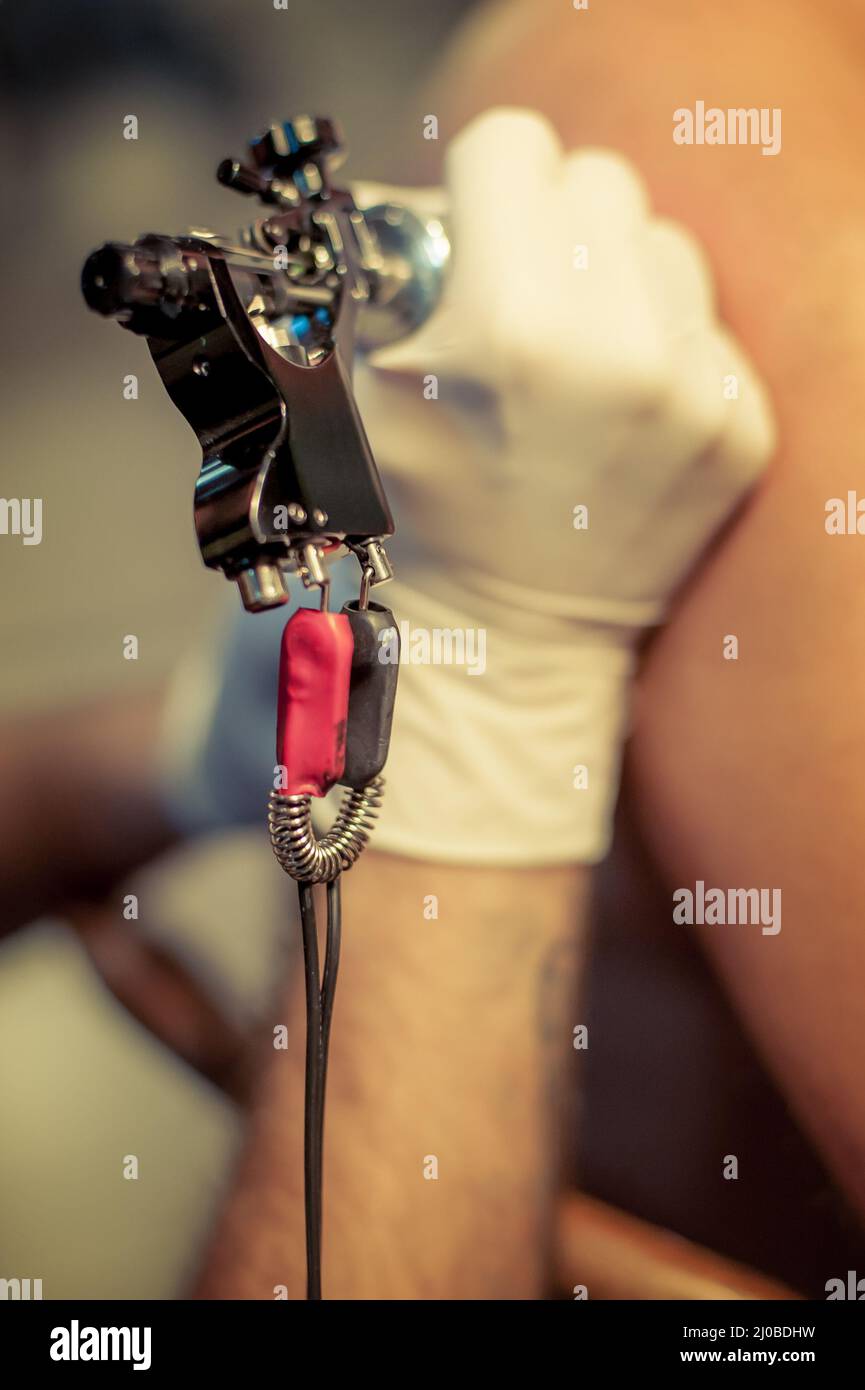 Master tatuaggio disegna la vernice blu sul tatuaggio del cliente Foto Stock
