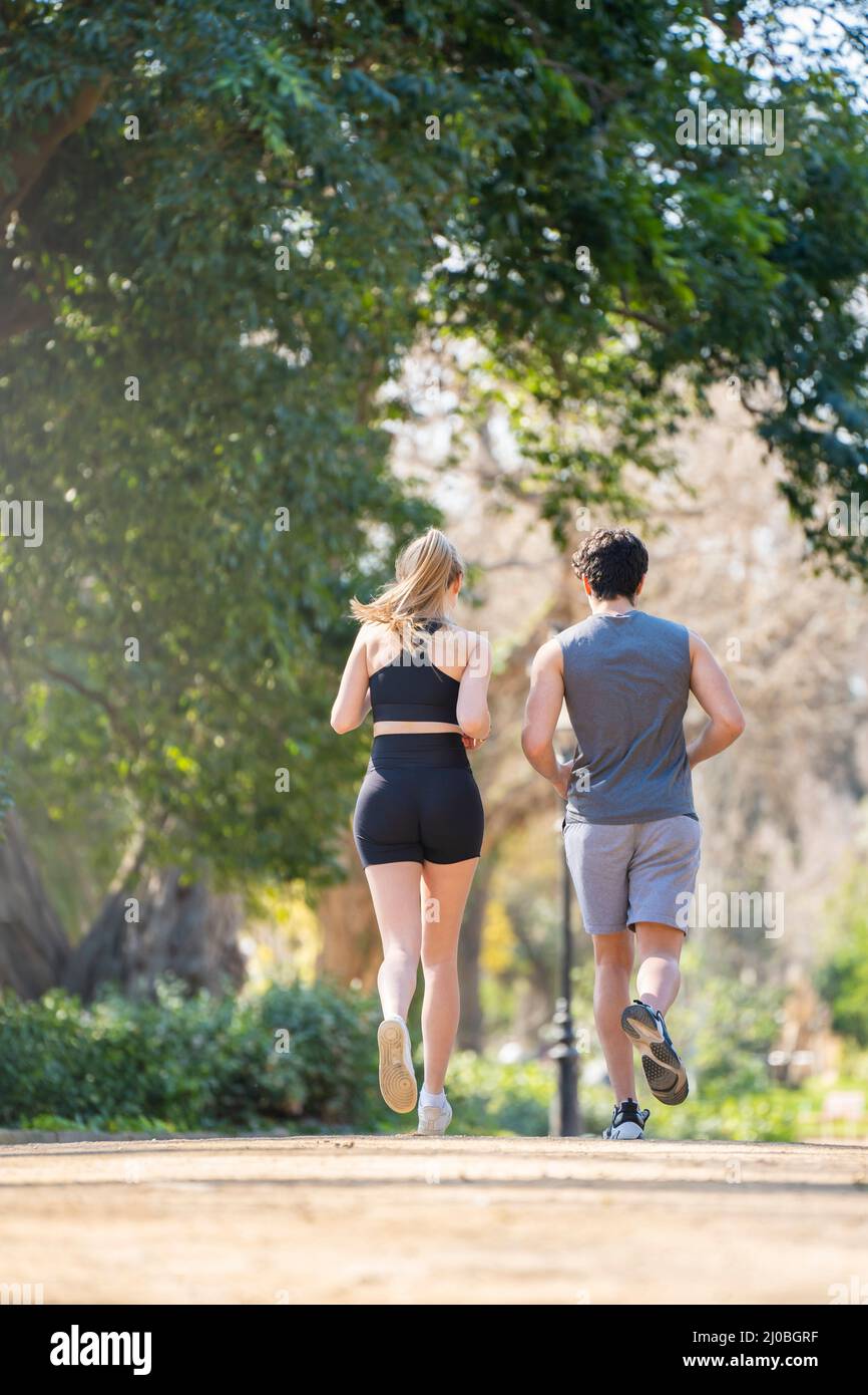 Vista posteriore della giovane coppia che fa sport che corre su un sentiero del parco Foto Stock