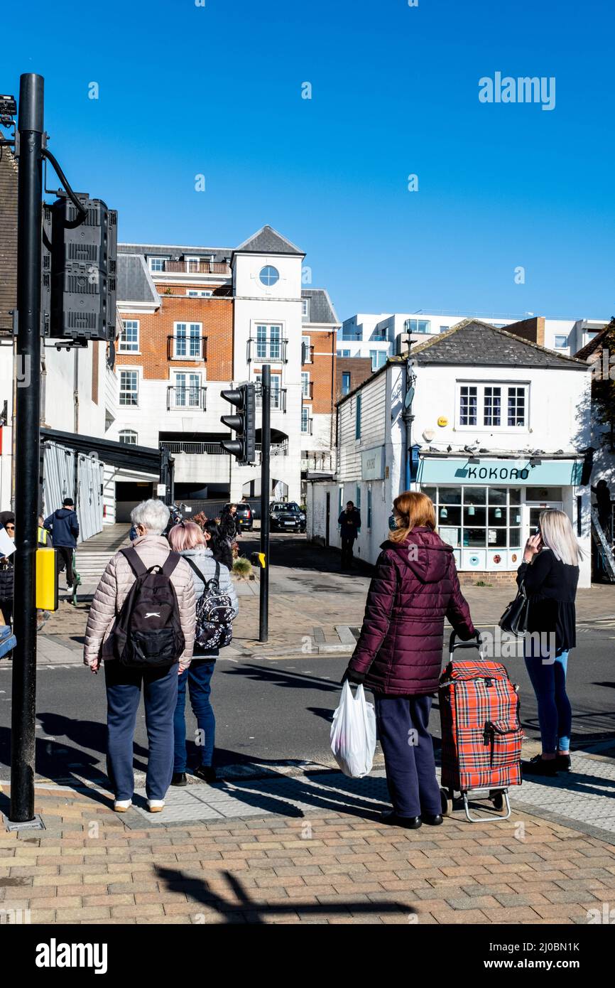Epsom Surrey London UK, marzo 17 2022, piccolo gruppo di persone in attesa di attraversare Una strada al semaforo Foto Stock