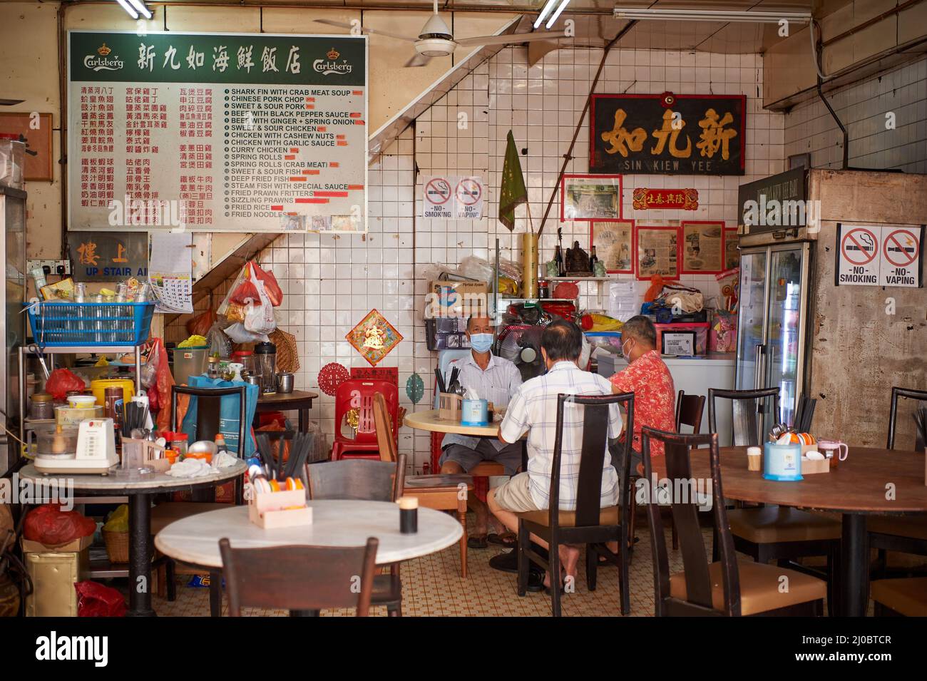Piccolo gruppo di anziani cinesi che si gustano la prima colazione in un tradizionale Kopitiam Foto Stock
