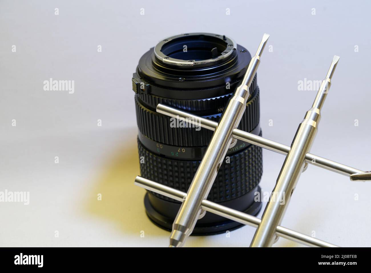 Obiettivo della fotocamera con chiave in metallo per la pulizia dell'obiettivo su sfondo bianco Foto Stock