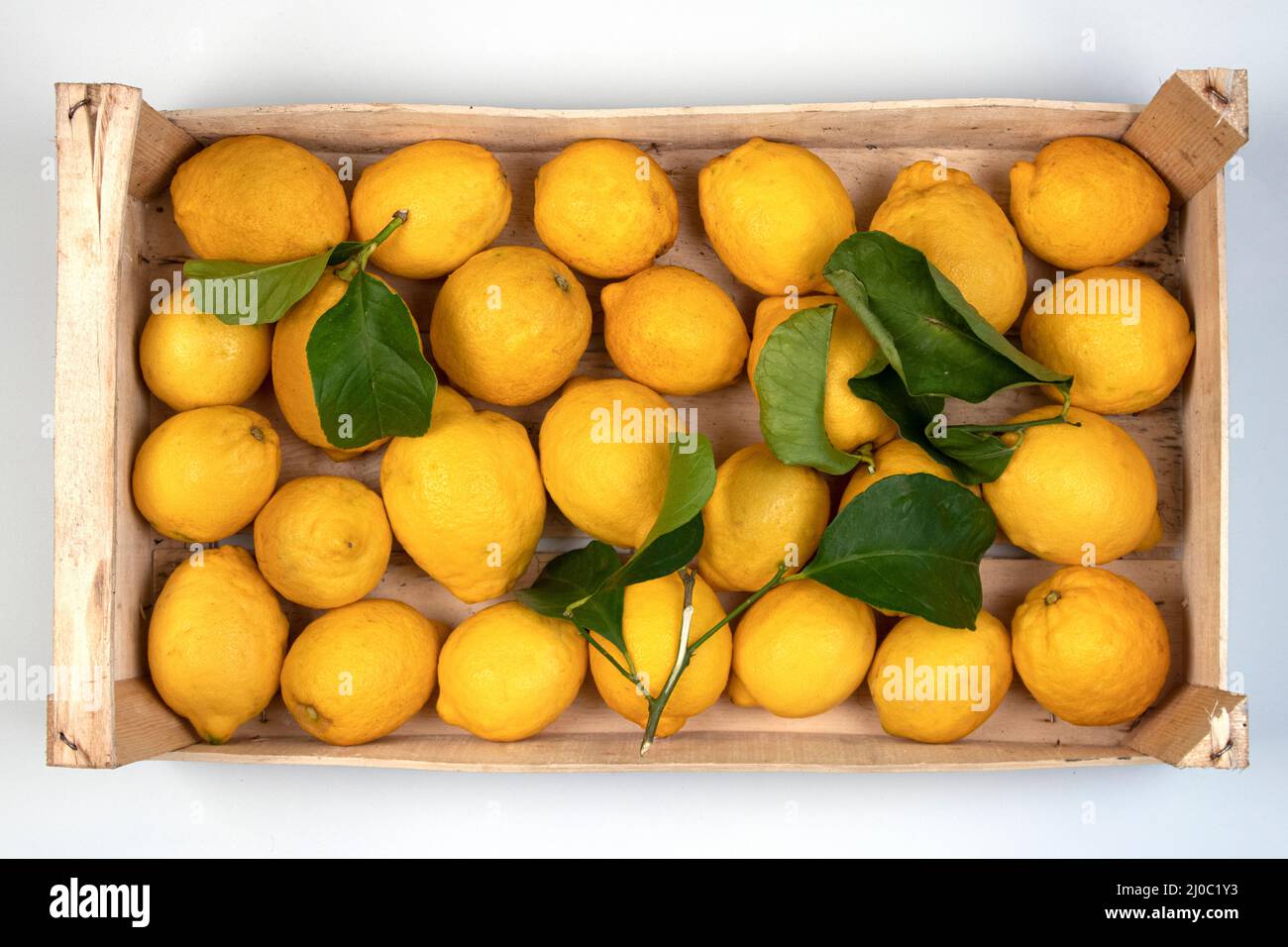 Limoni in una scatola di legno al mercato pronto per la vendita, tagliato su bianco Foto Stock