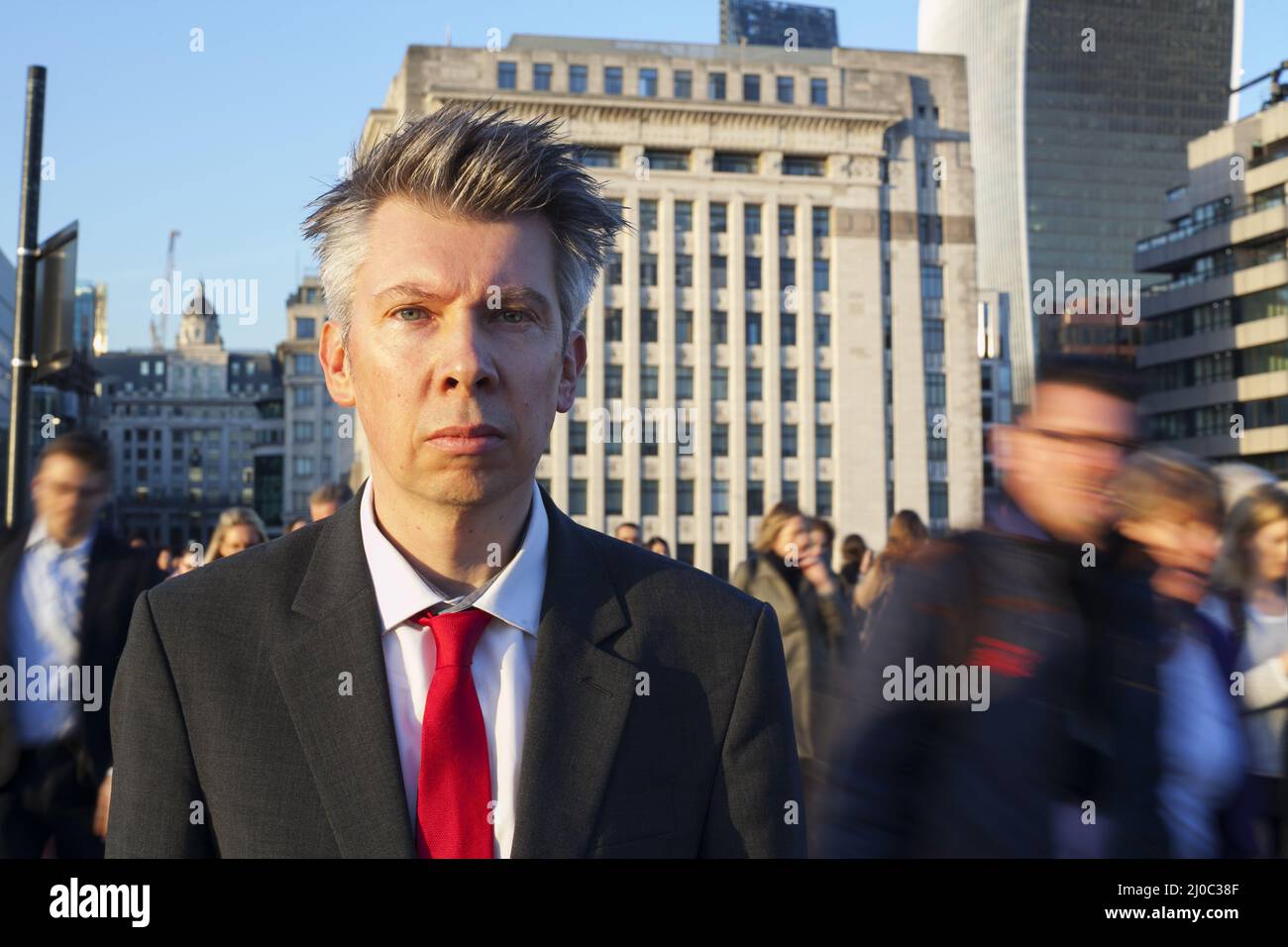 Uomo d'affari fermo mentre la gente cammina dietro Foto Stock