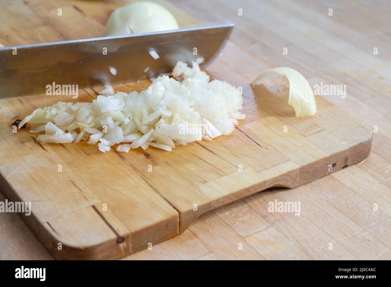 La grande lama da cucina taglia le cipolle in piccoli cubetti su